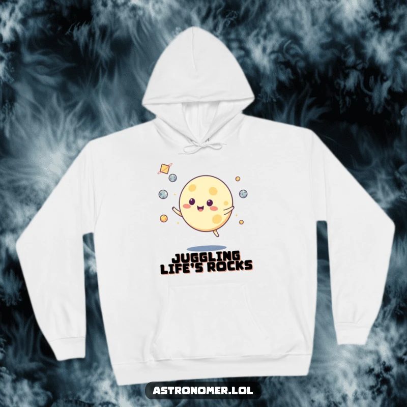Funny hoodie with a happy moon character juggling luminous asteroids, set against a backdrop of stars, making it cozy and cool.