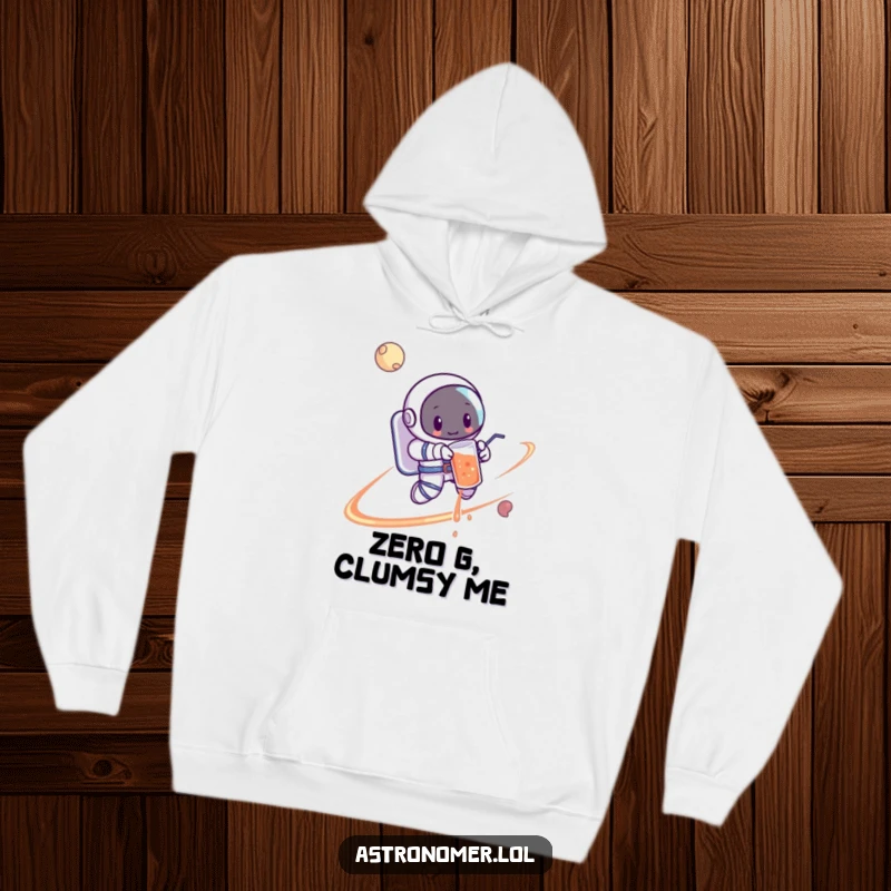 Funny Astronaut Hoodie: A cartoon astronaut in orbit awkwardly spilling a drink around a vibrant planet, a moment of zero-G chaos.